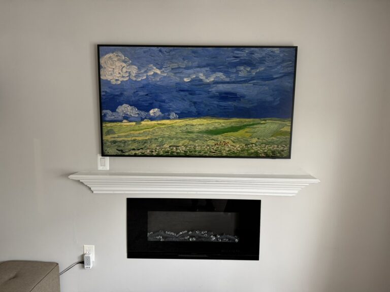Art-mode TV above a white mantel and linear fireplace