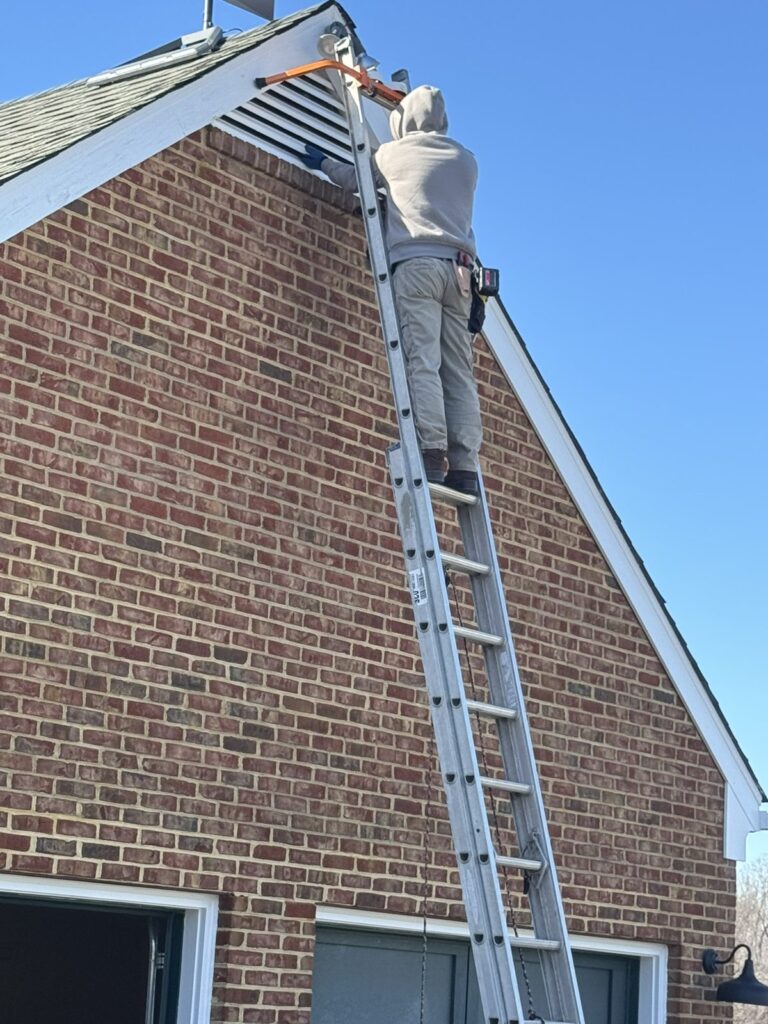 Installer on a tall ladder at a brick gable